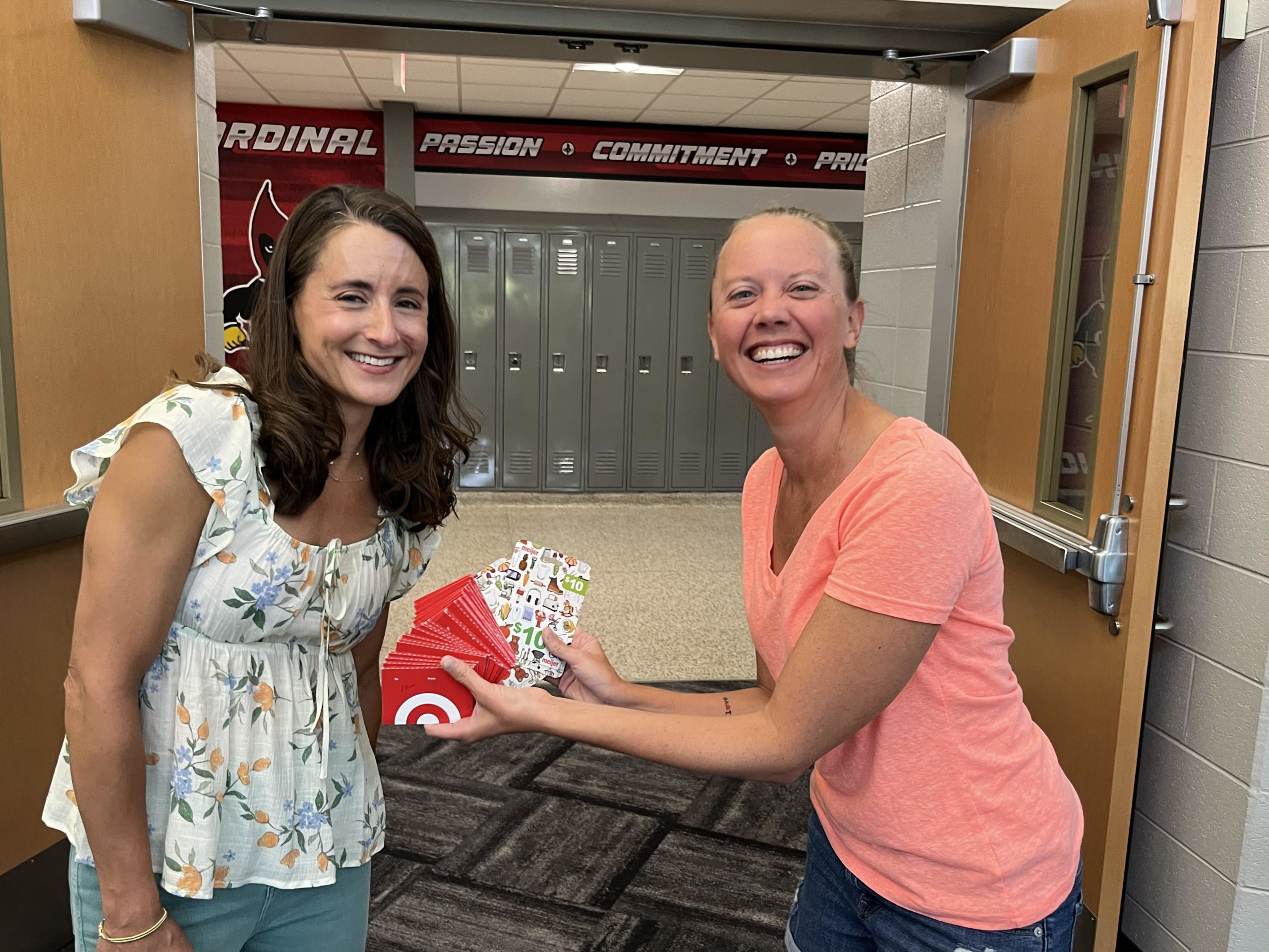 A member of the Alliance handing a large collection of gift cards to the president of the EAW